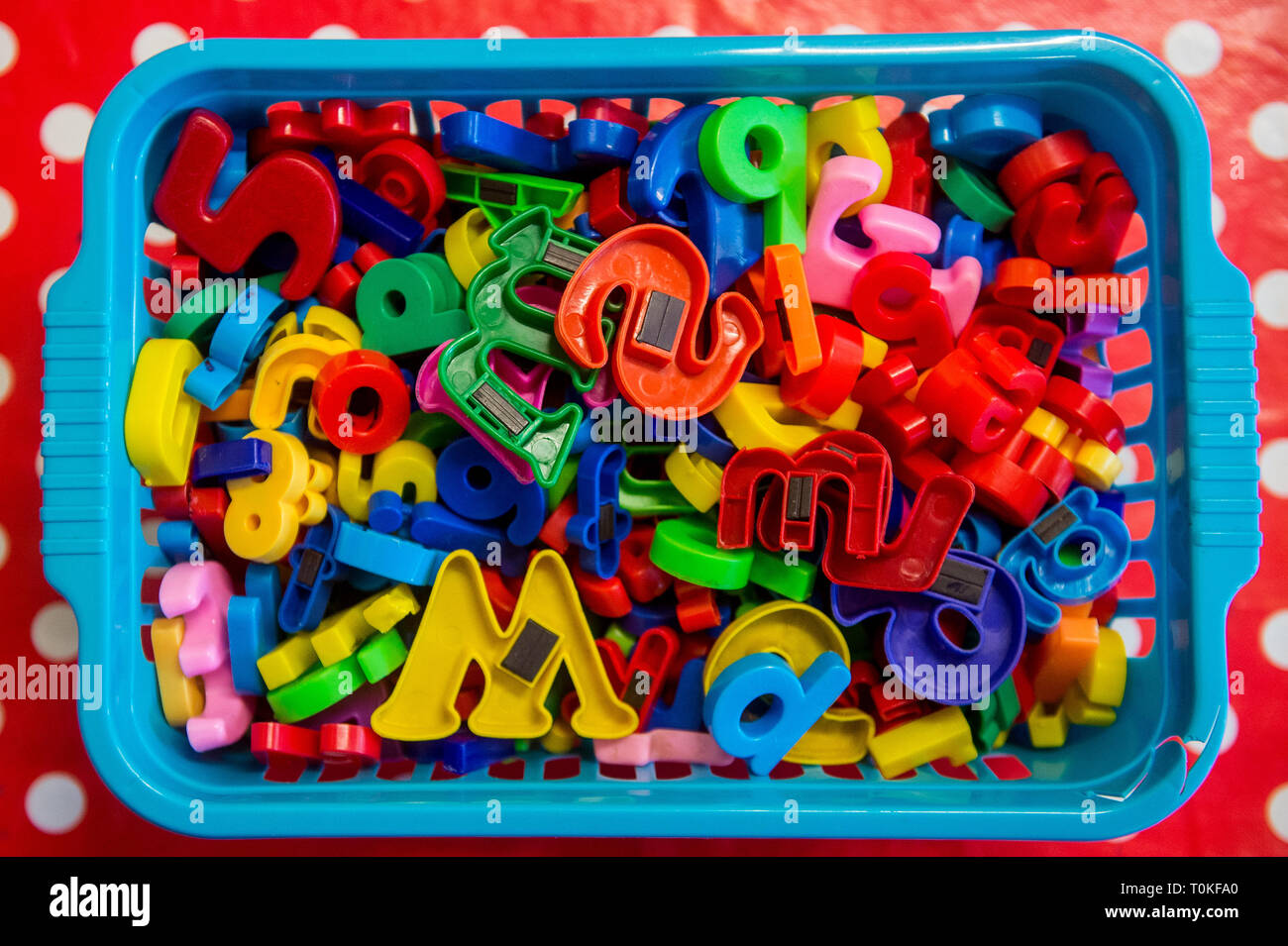 Plastic basket filled with colourful magnetic letters that you might put on a fridge or notice board Stock Photo