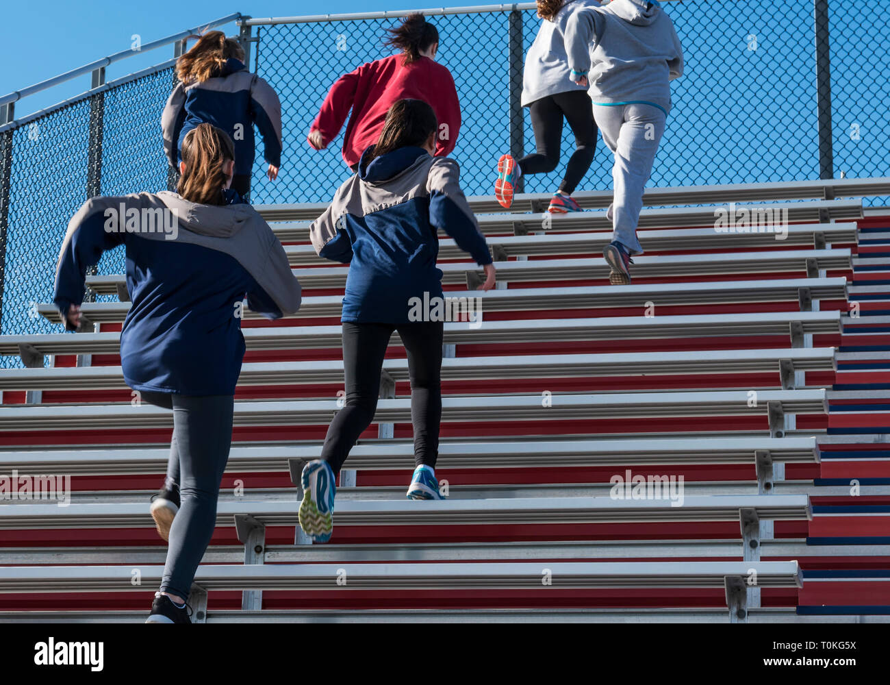 A high school girls track and field team running up the bleachers on a
