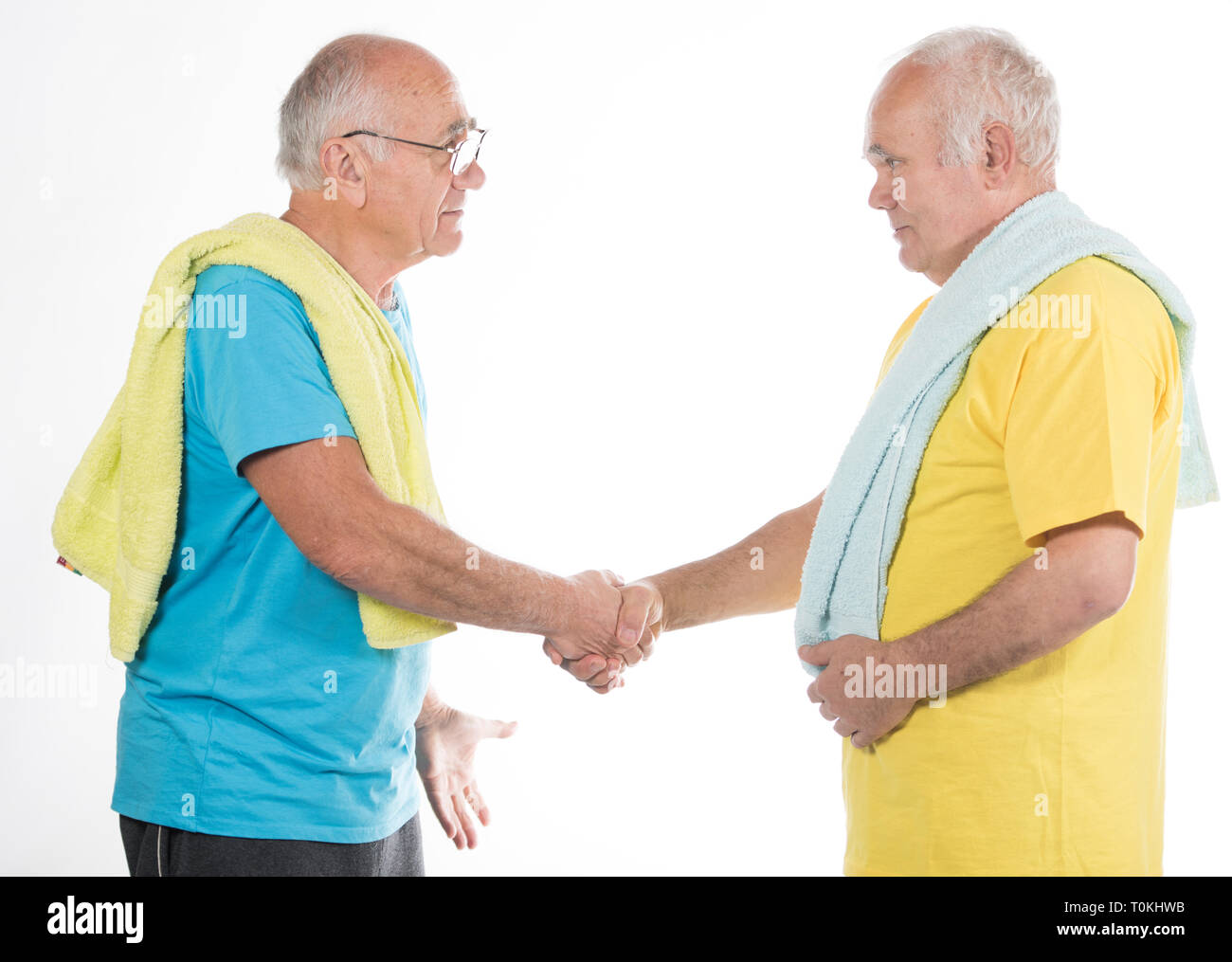 two happy smiling senior men after sport training with yellow and blue t-shirts and towels Stock Photo