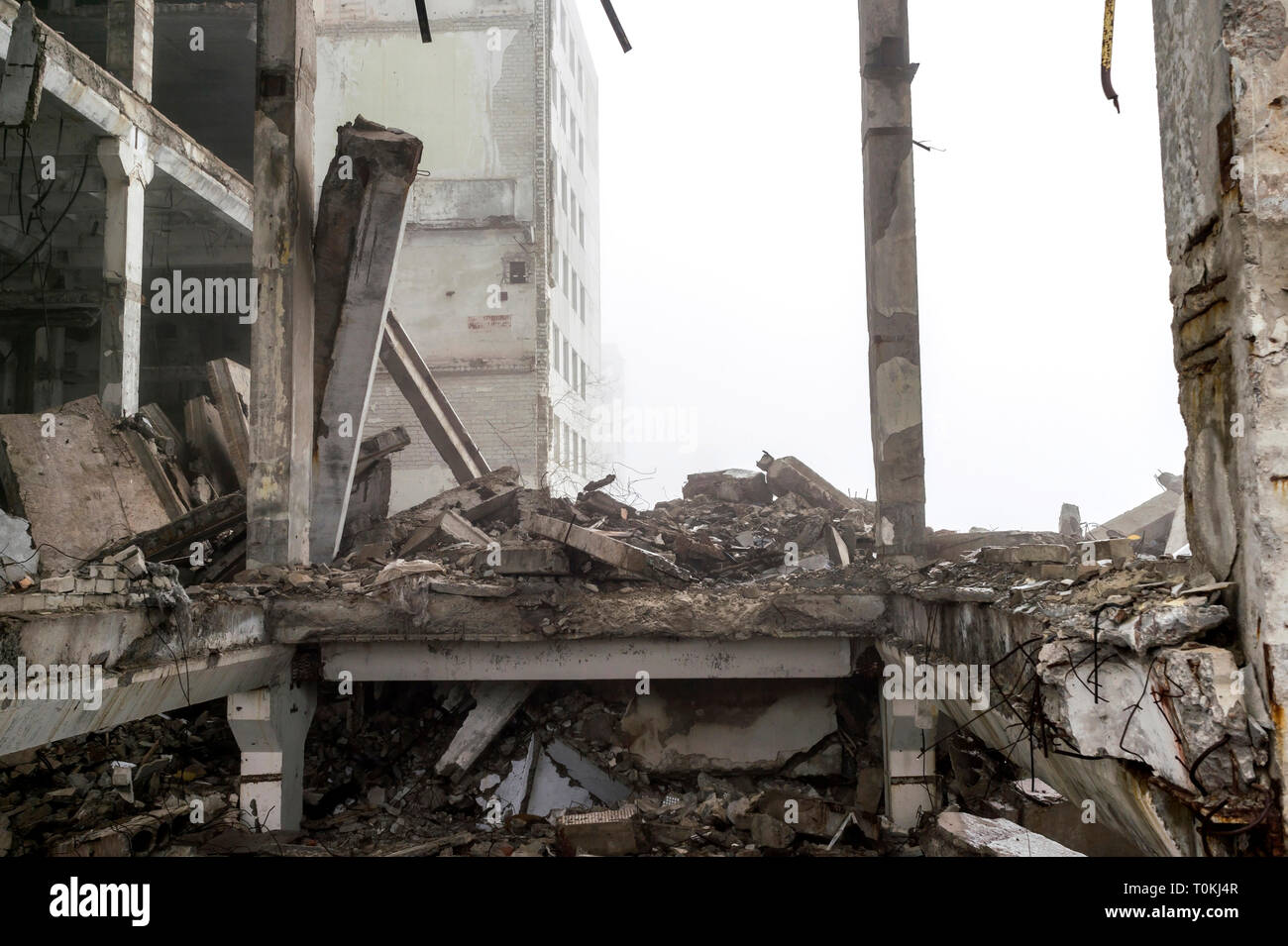 The remains of a large building destroyed in a foggy haze. Concrete ...