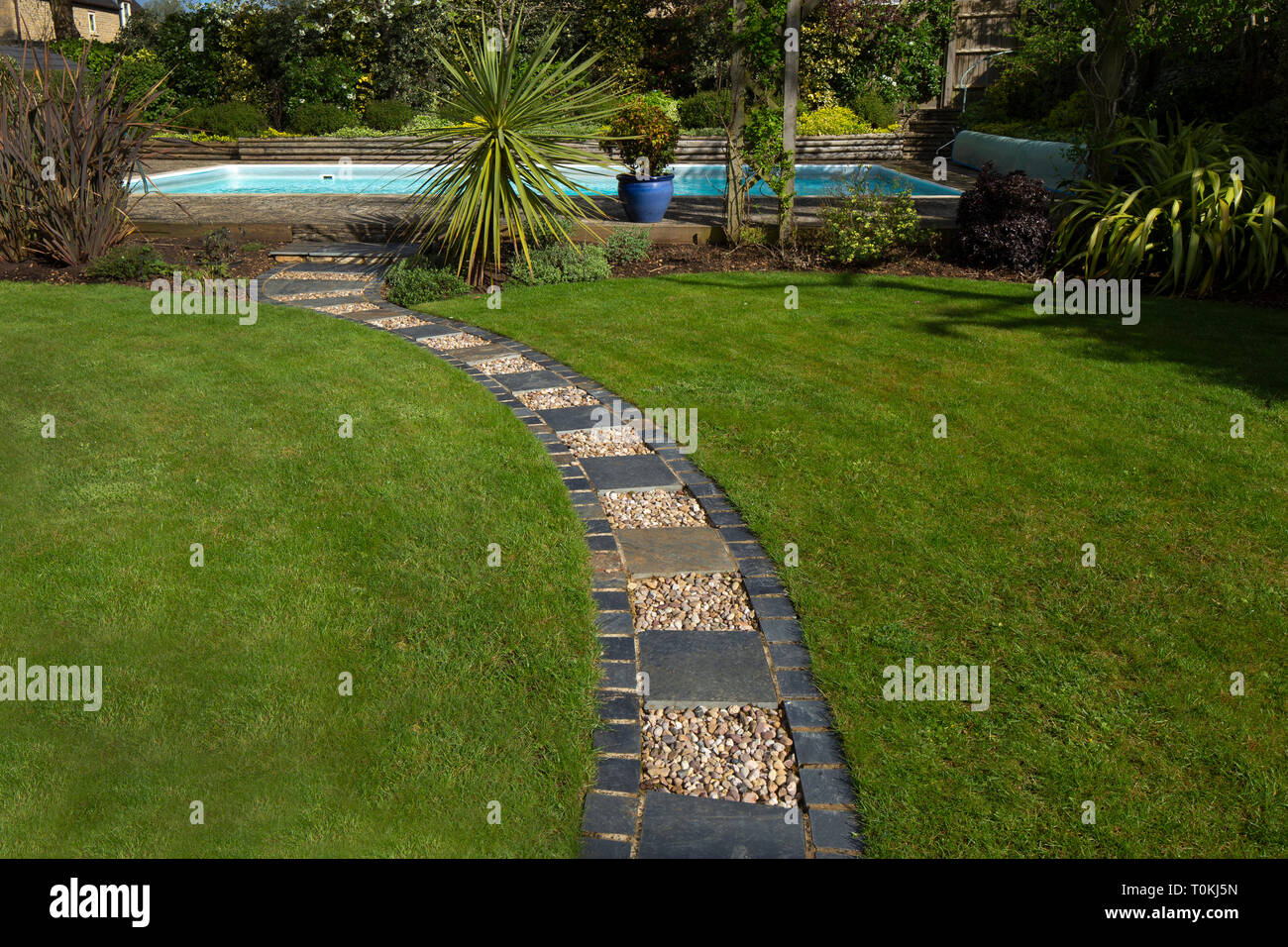 Gravel and stone edged path across lawn in English Garden Stock Photo