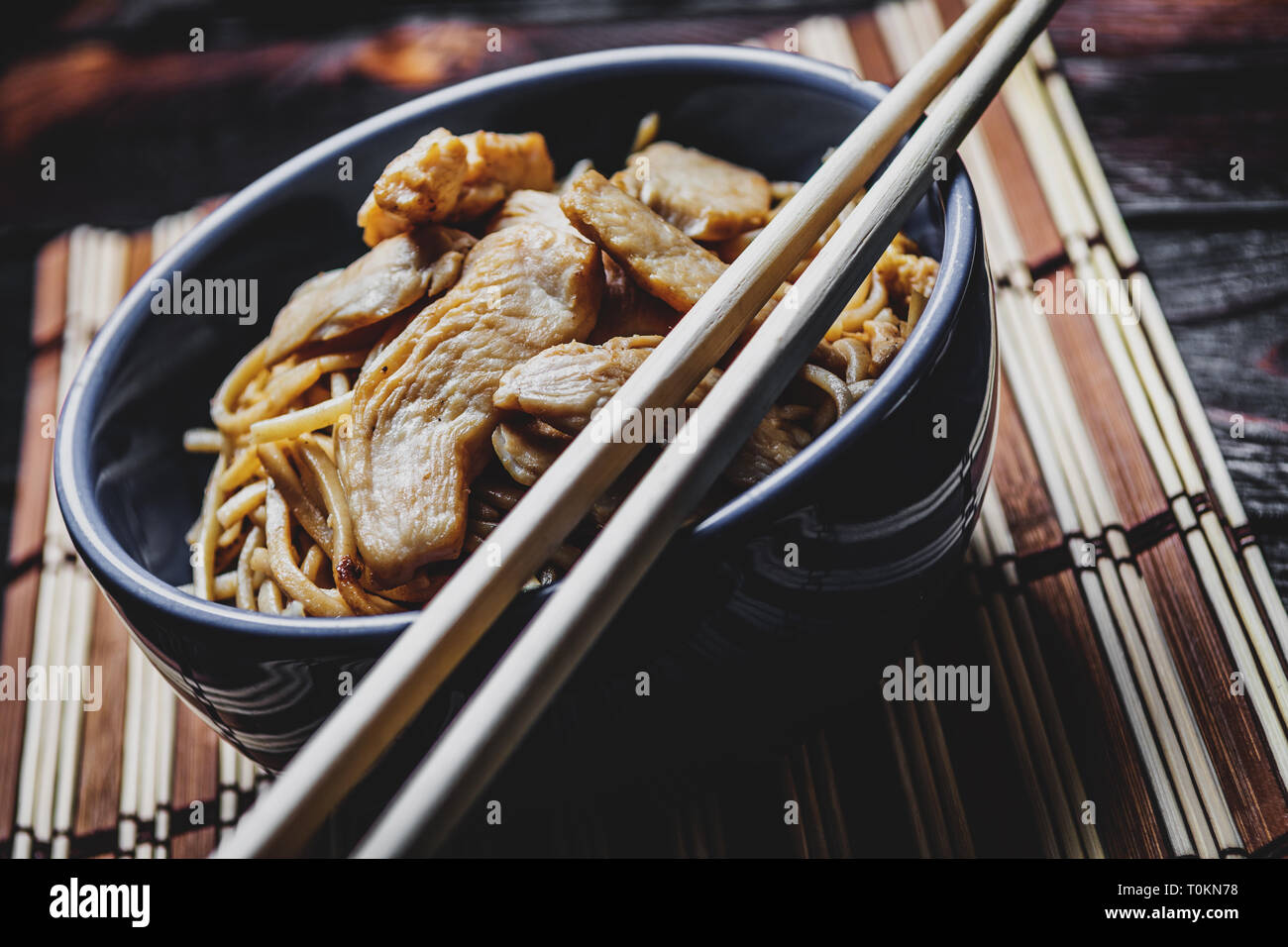 Traditional asian or chines noodles with chicken meat on bowl with chopsticks on wood table Stock Photo