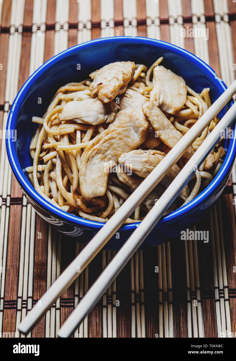 Traditional asian or chines noodles with chicken meat on bowl with chopsticks on wood table Stock Photo