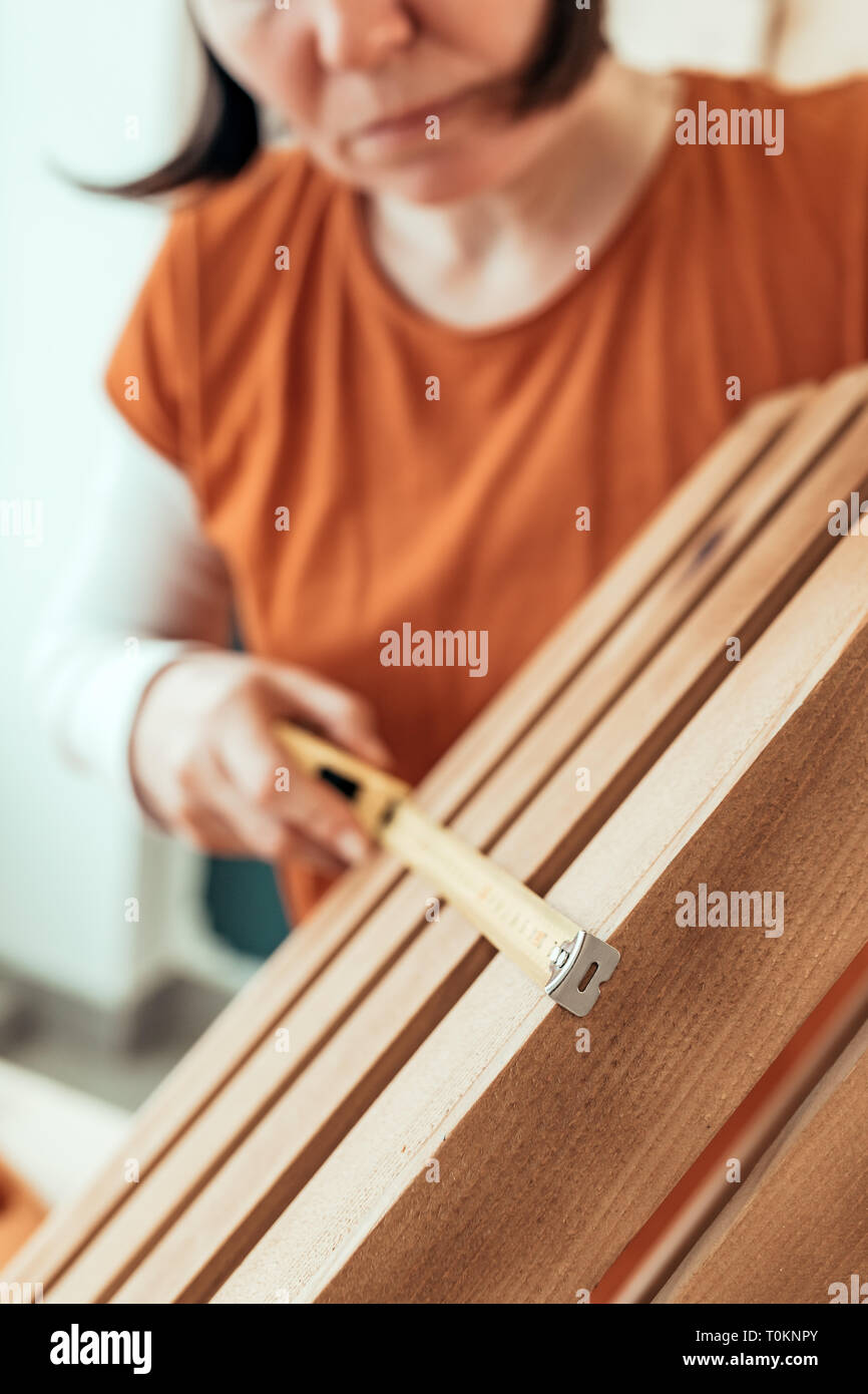 Female carpenter tape measuring wooden crate in her small business woodwork workshop Stock Photo