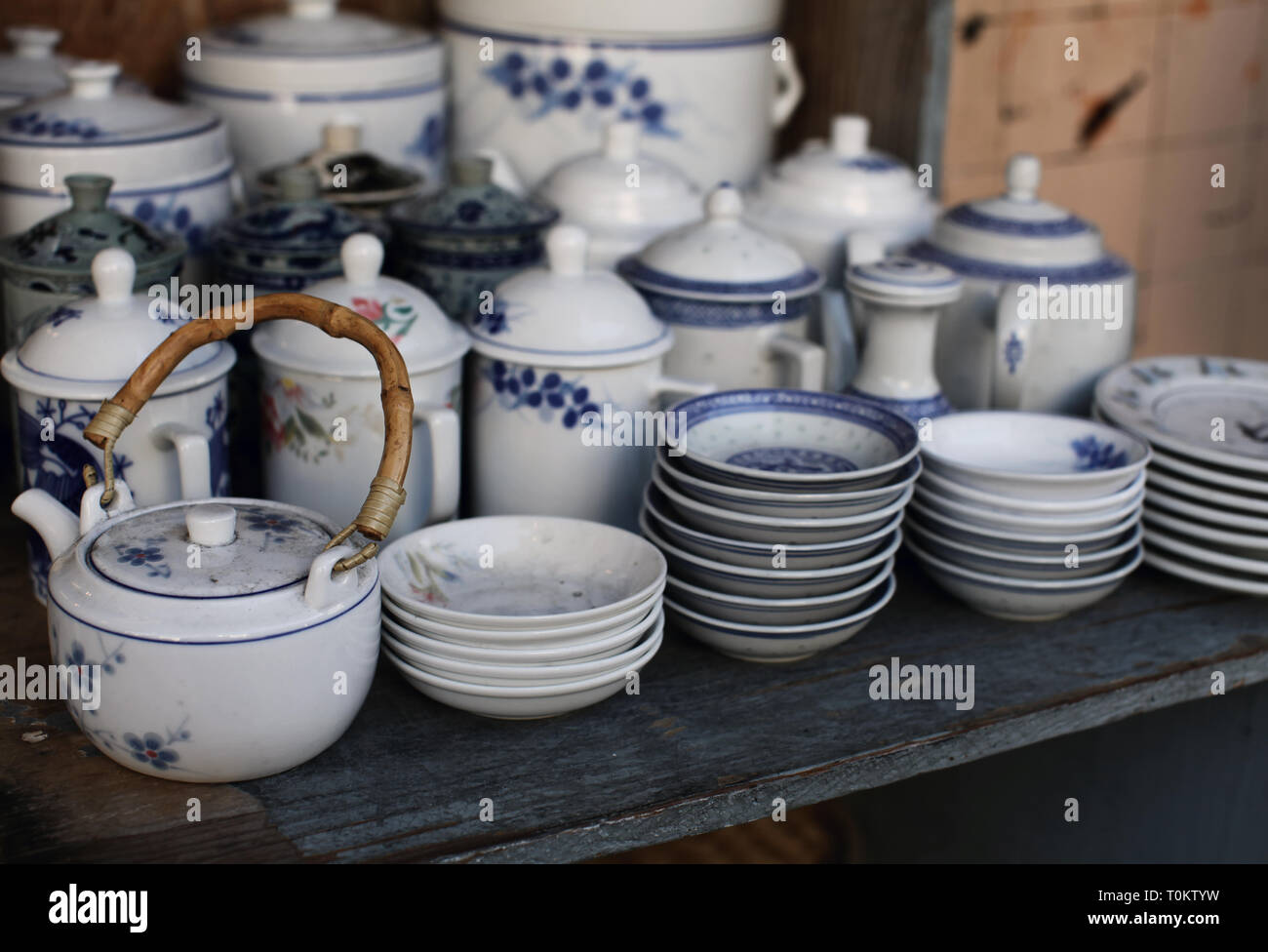 Stacks of porcelain dishes and teapots on display for sell at a market