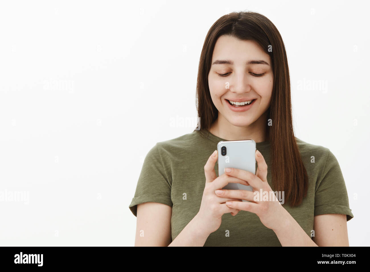 Girl scrolling funny memes via smartphone laughing and having fun holding mobile  phone near face grinning and looking amused and pleased at cellphone Stock  Photo - Alamy