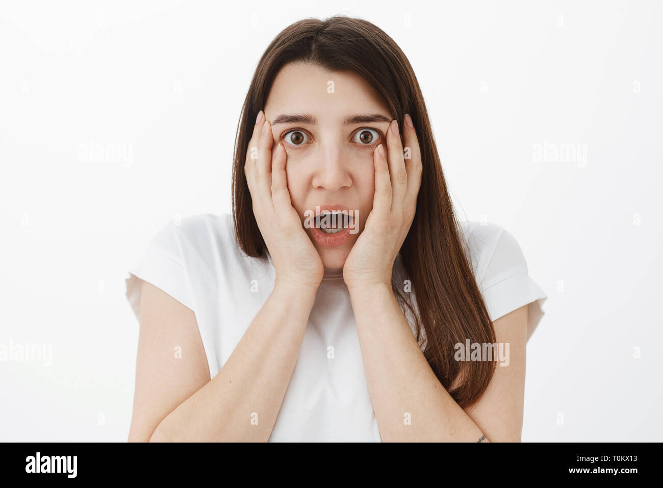 Close-up shot of shocked and speechless concerned young girl hearing shocking rumor gasping dropping jaw from unbelievable news holding hands on Stock Photo