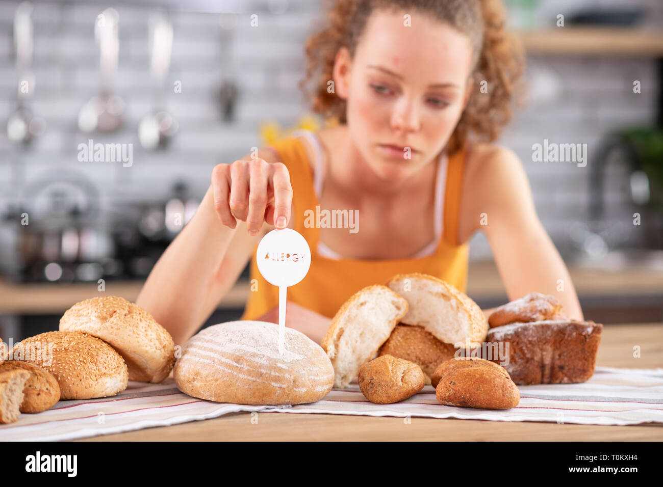 Upset long-haired woman touching allergy warning nameplate Stock Photo