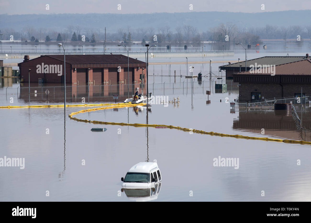 Contracted employees of the Environmental Restoration, LLC company deploy a spill containment boom around the Offutt Air Force Base fuel storage area as a precautionary measure March 18, 2019 following flooding of the southeast portion of the base. An increase in water levels of surrounding rivers and waterways caused by record-setting snowfall over the winter in addition to a large drop in air pressure caused widespread flooding across the state of Nebraska. (U.S. Air Force photo by Delanie Stafford) Stock Photo