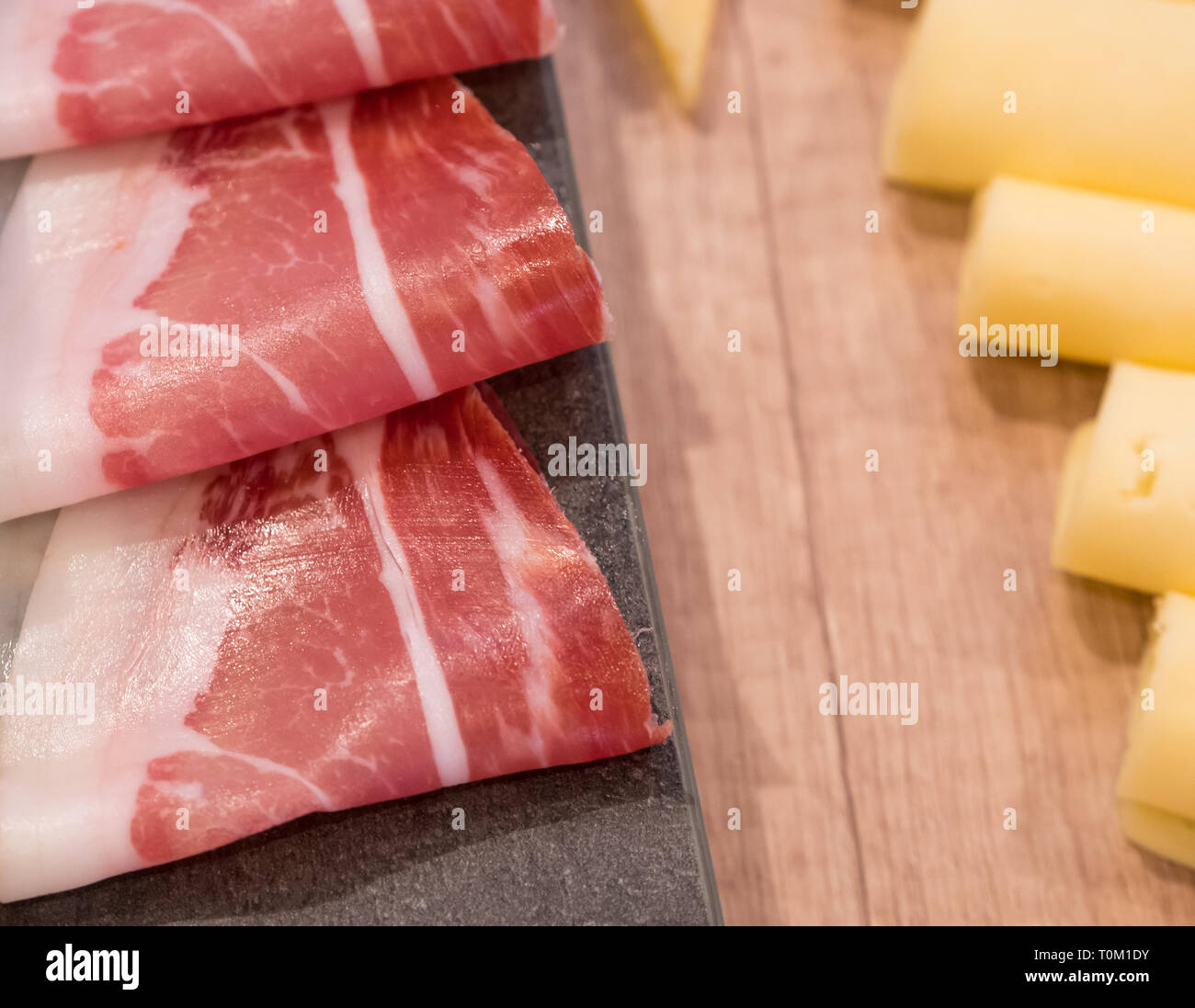 Smoked ham and cheese on rustic wooden board in restaurant Stock Photo