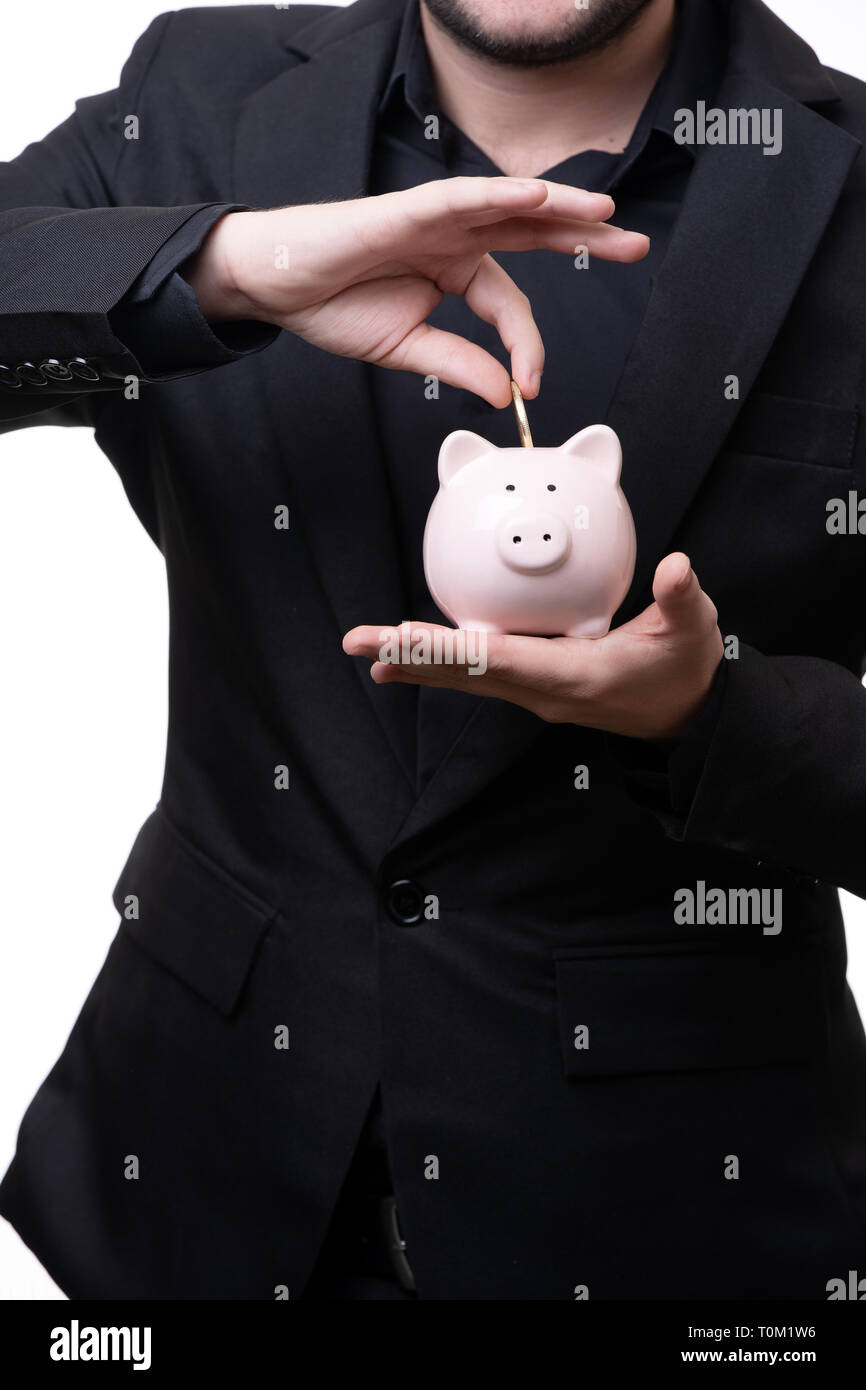 Man in black suit puts coin in piggy bank Stock Photo - Alamy