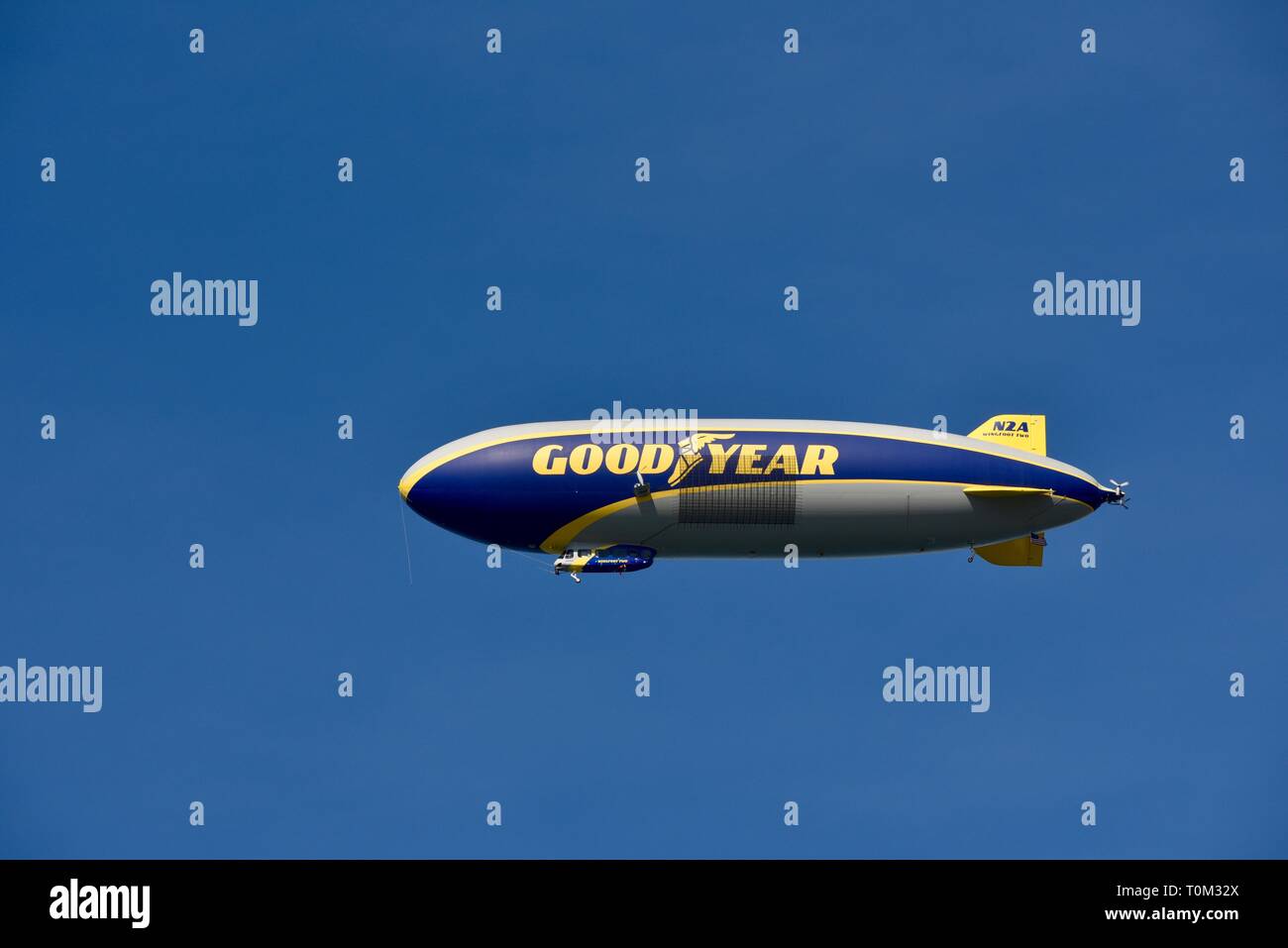 Famous Goodyear blimp dirigible soaring overhead in flight in bright blue sky, outside sporting event, PGA golf tournament, San Diego, CA, USA. Stock Photo