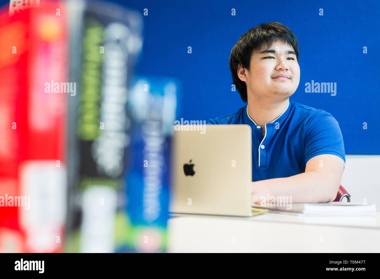 An international asian young male student sits in a classroom at a desk ...