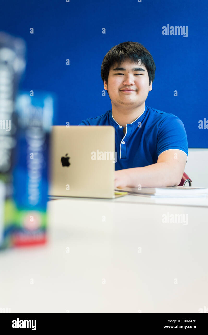 An international asian young male student sits in a classroom at a desk ...