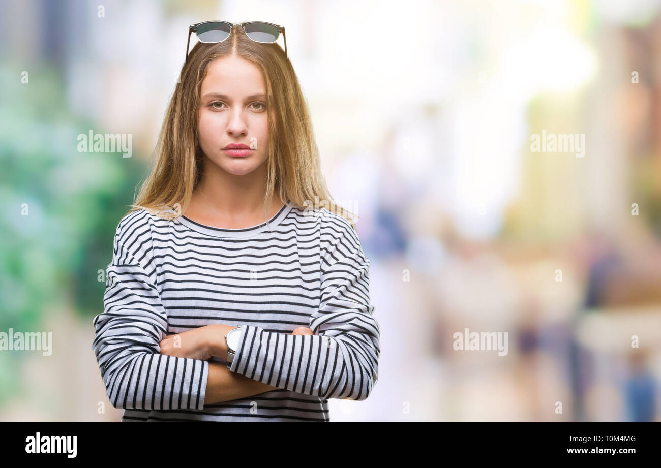 Young beautiful blonde woman wearing sunglasses over isolated background skeptic and nervous, disapproving expression on face with crossed arms. Negat Stock Photo