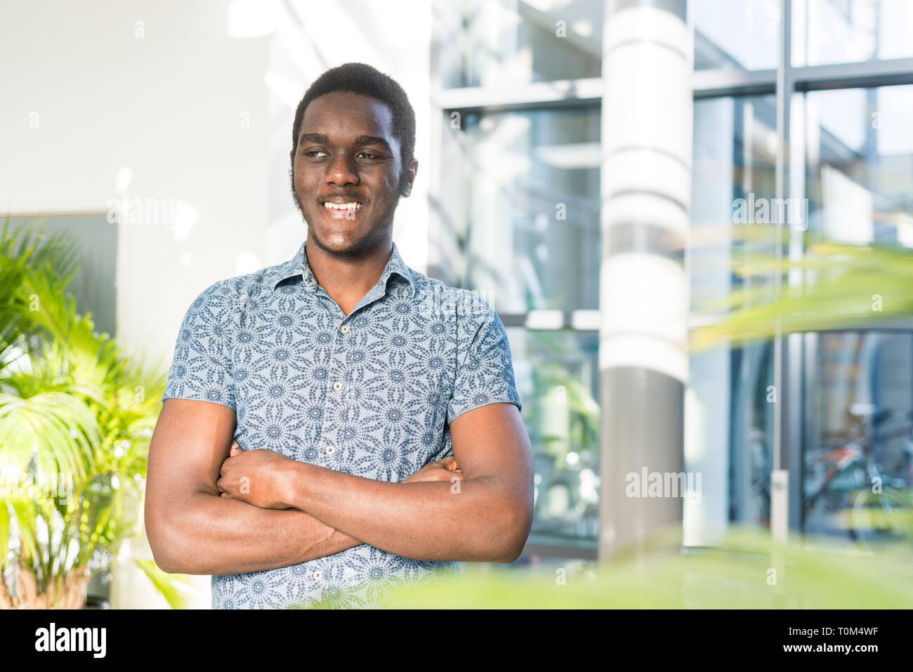 A young black international student stands in the corridors on campus ...