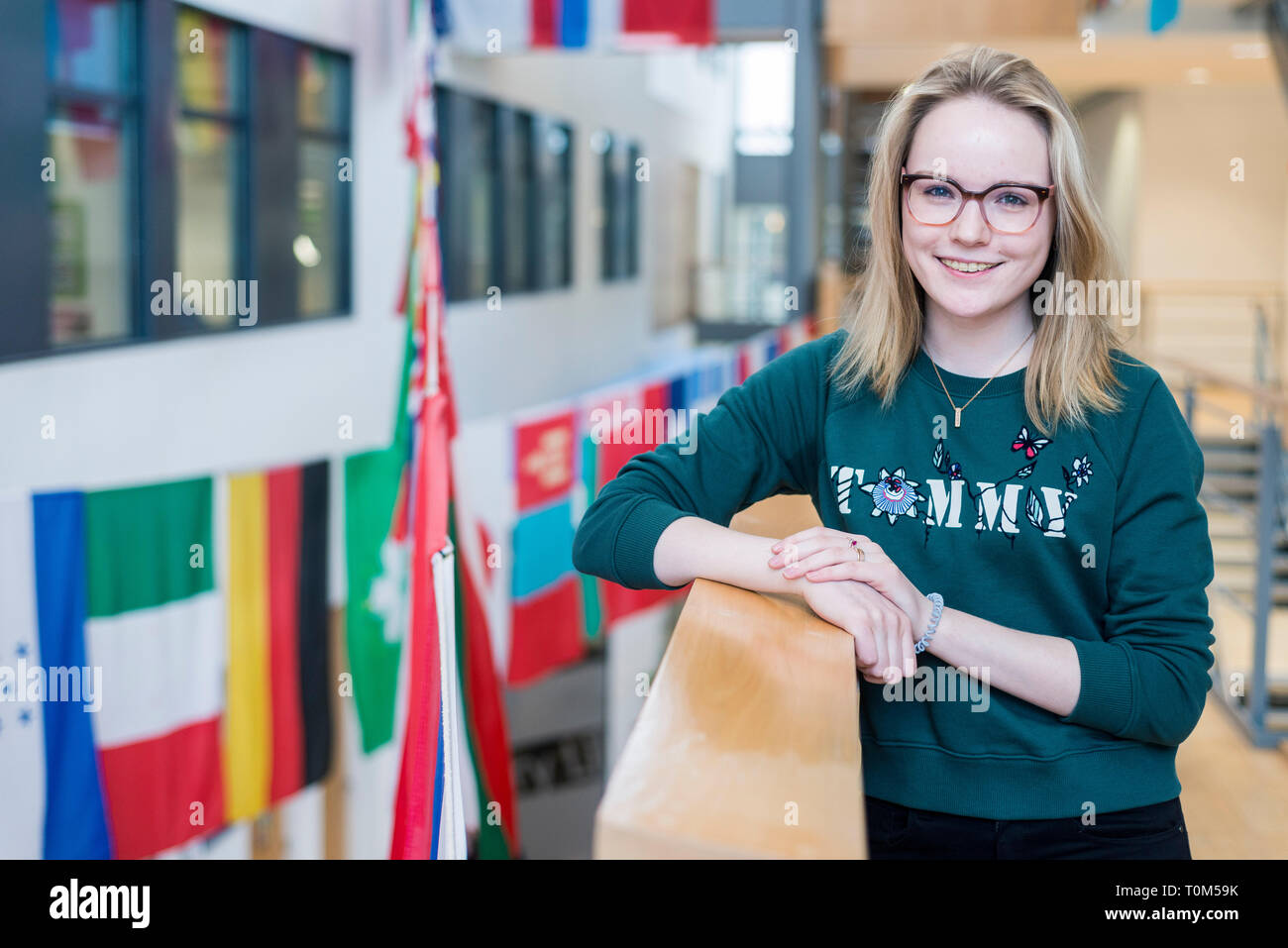 A young international european student stands with the flags on a ...