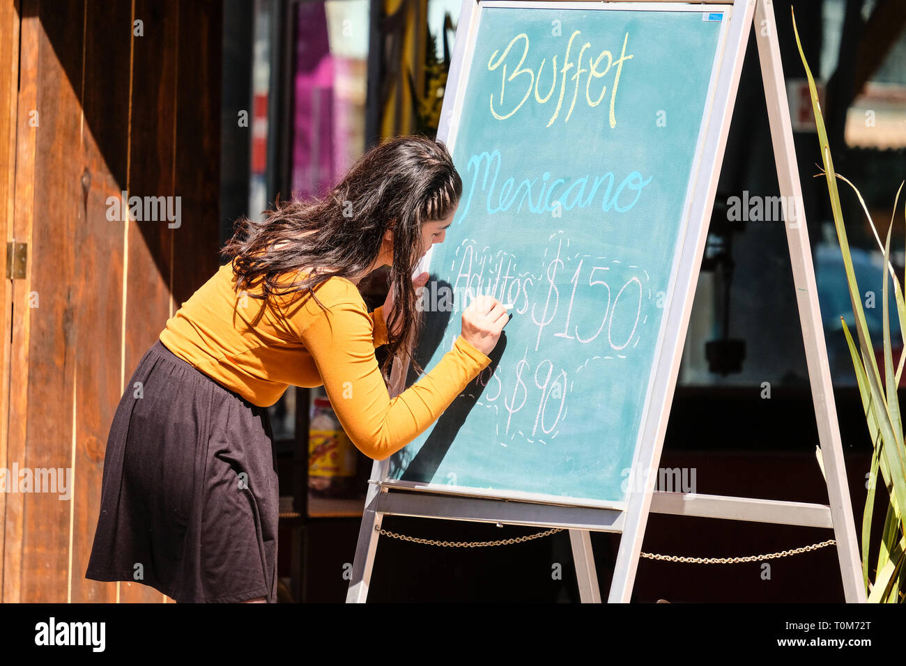 A young pretty Mexican woman writing buffet menu on a board outside a  Mexican restaurant in Cholula Puebla Mexico Stock Photo - Alamy