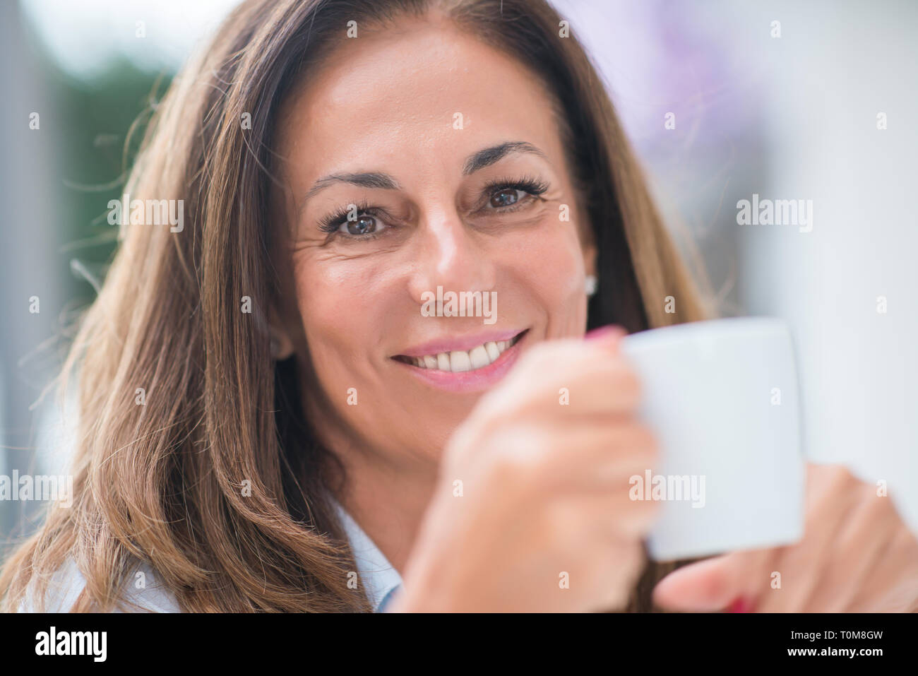 Beautiful middle age hispanic woman at cafeteria with smile on face at