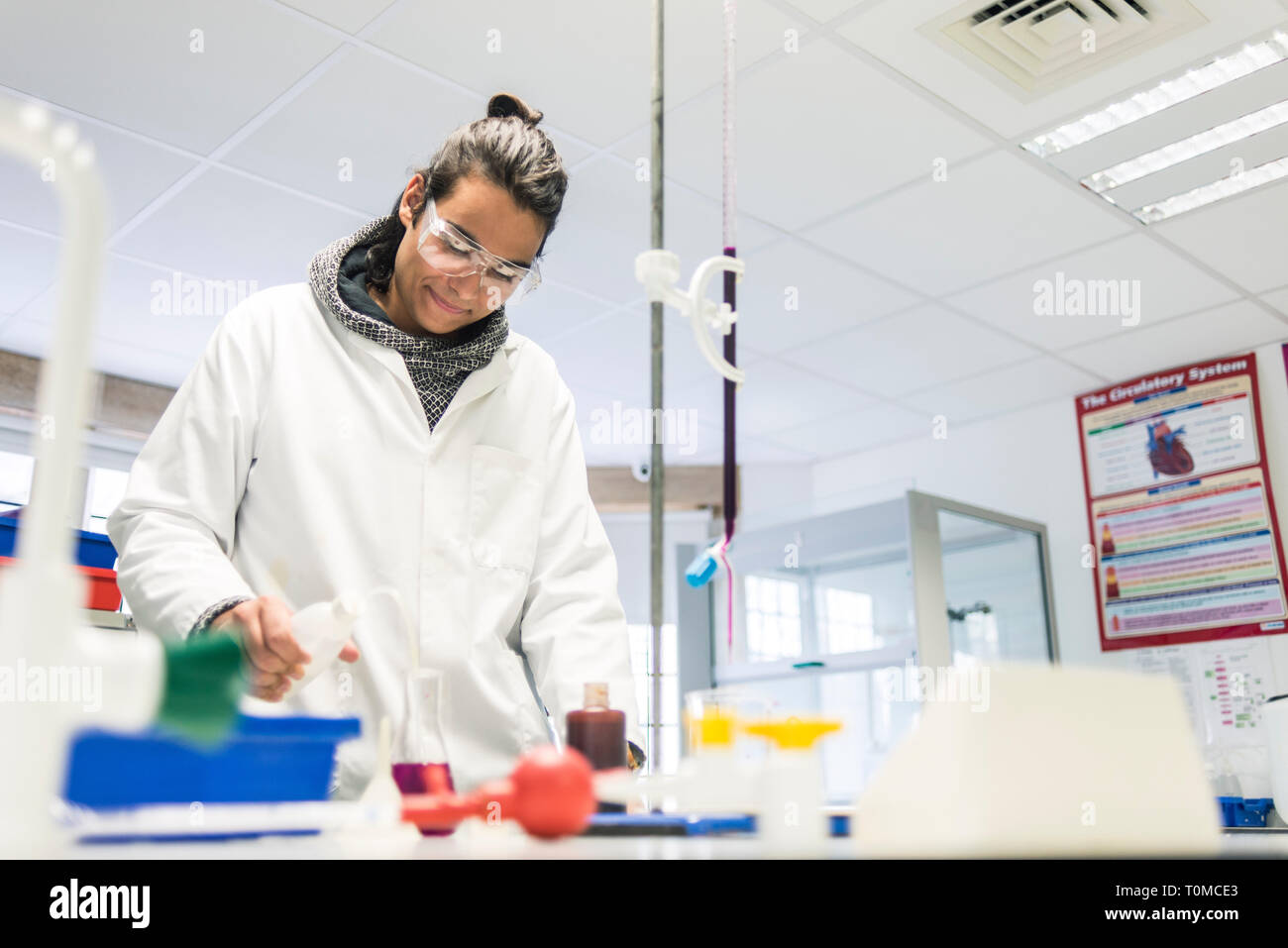 A young male student works in the science lab of a cambridge college in a white lab coat Stock Photo