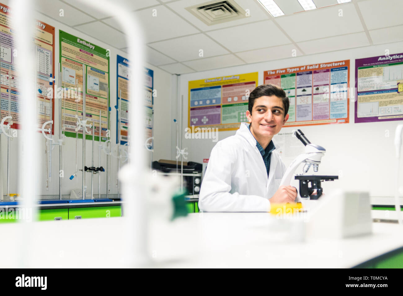 A young male student works in the science lab of a cambridge college in a white lab coat Stock Photo