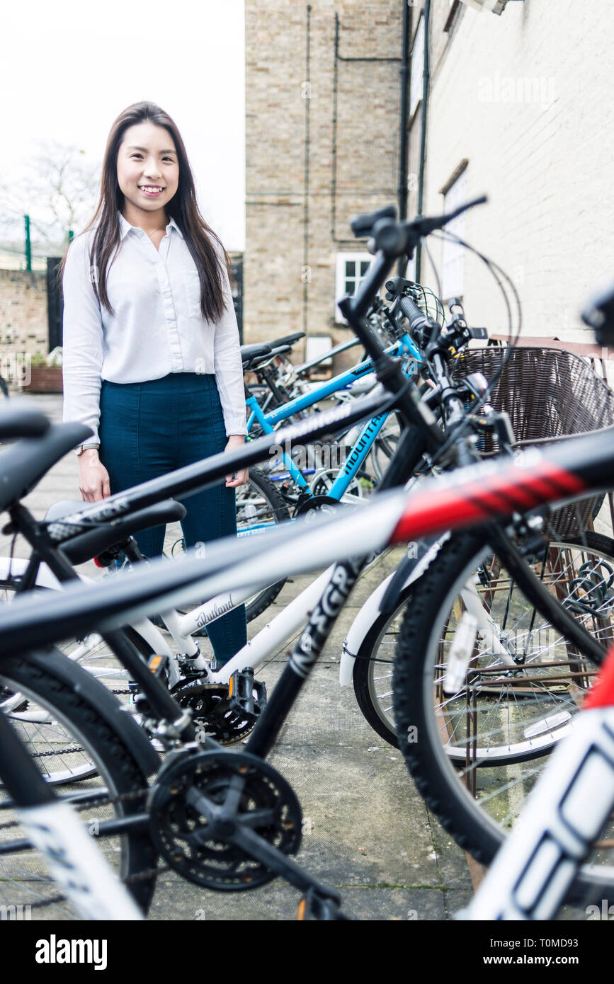 an international student stands amongst the bike storage and many bicycles Stock Photo