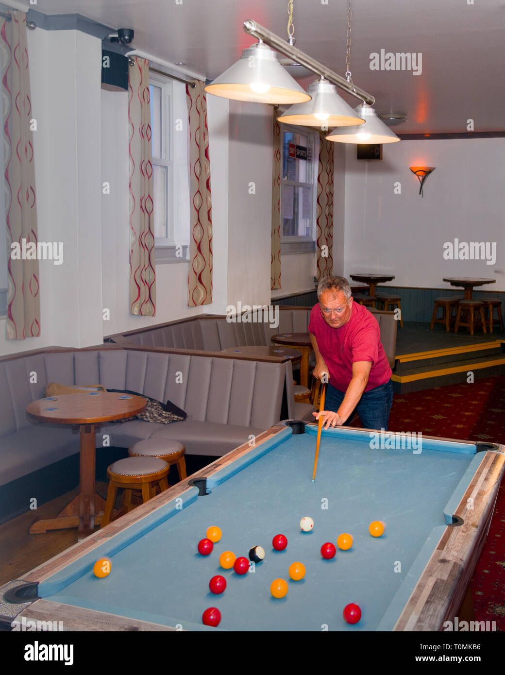 A middle aged pool player in specialed spectacles breaks the pack at the pool table Stock Photo