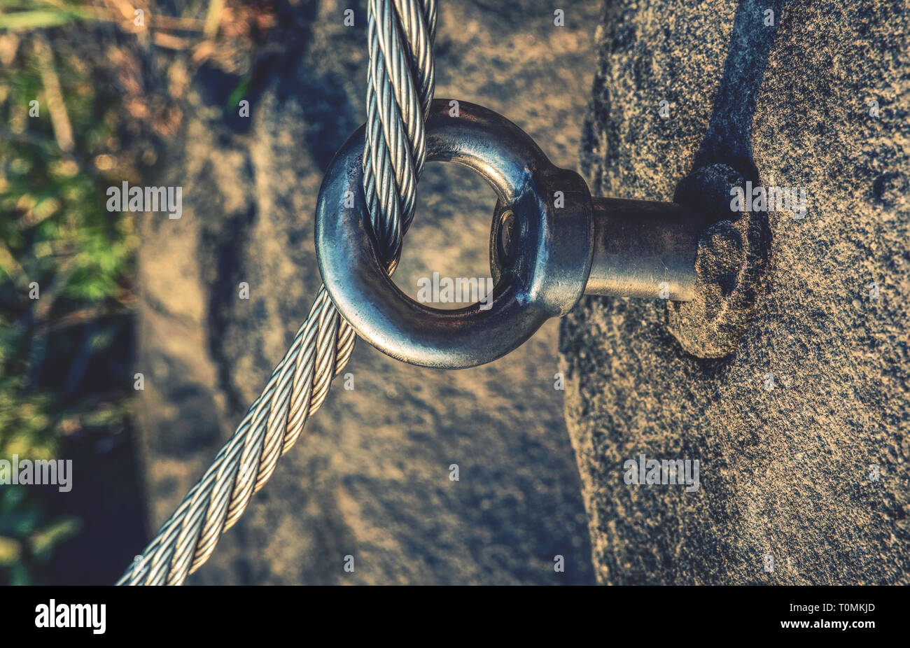Stainless twisted rope anchored in rocky wall. Stair climbing and iron
