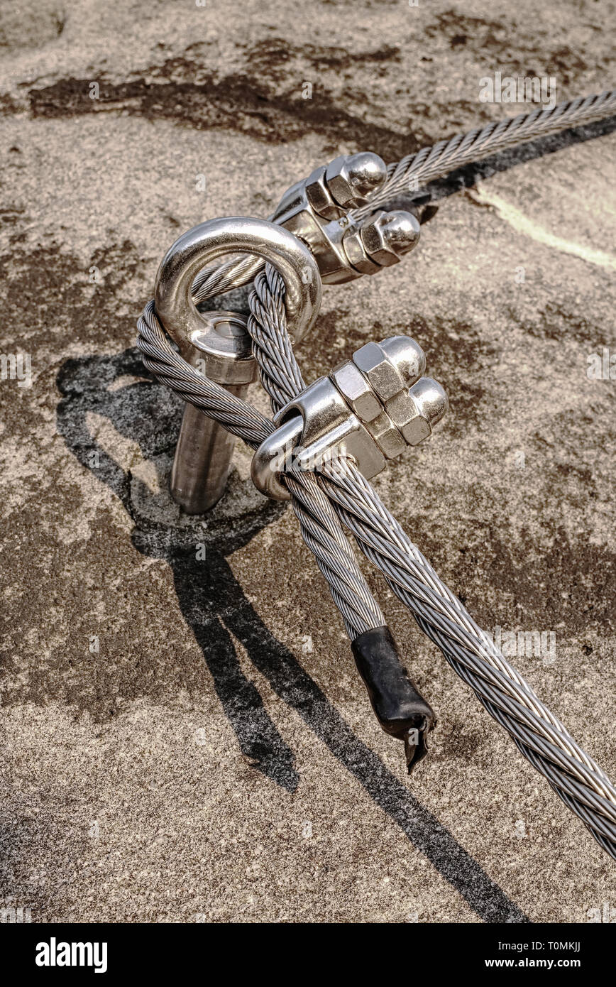 Climbing anchor or carabiner attached to the cliff rock. Difficult path