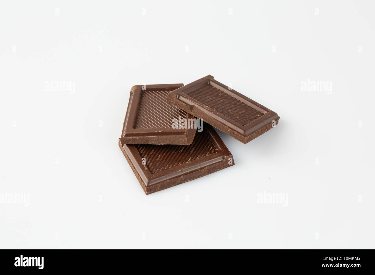 close up of chocolate pieces stack and chocolate syrup on white ...