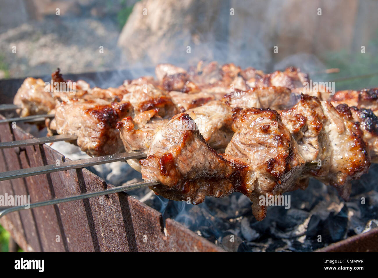 Grilled kebab cooking on metal skewer. Shashlik made of cubes of meat