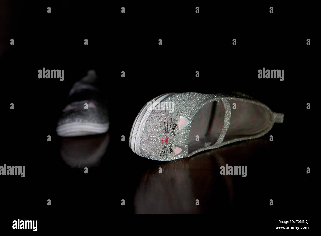 Girly Cat Shoes lying around on the floor untidily in low key lighting Conceptual Stock Photo