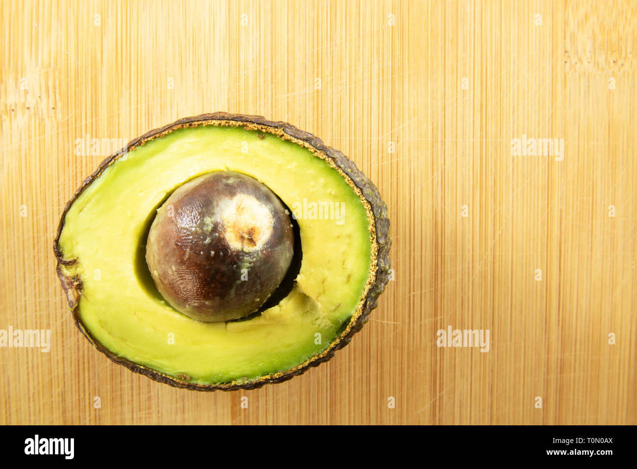 Avocado half sliced on wood background Stock Photo