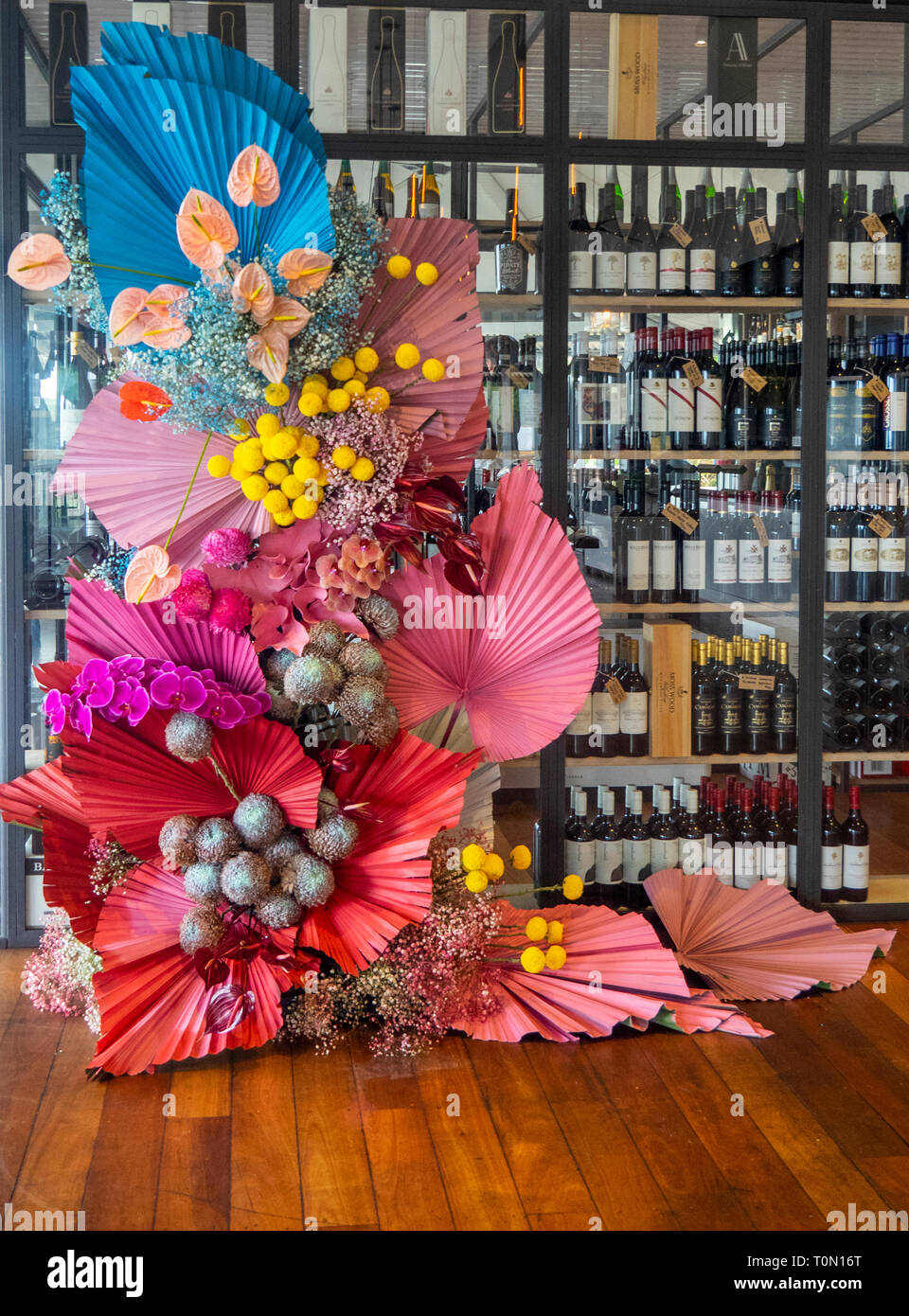 Large flower arrangement on wooden jarrah floorboards in front of red wine bottles in Thomsons Restaurant Rottnest Island WA Australia. Stock Photo