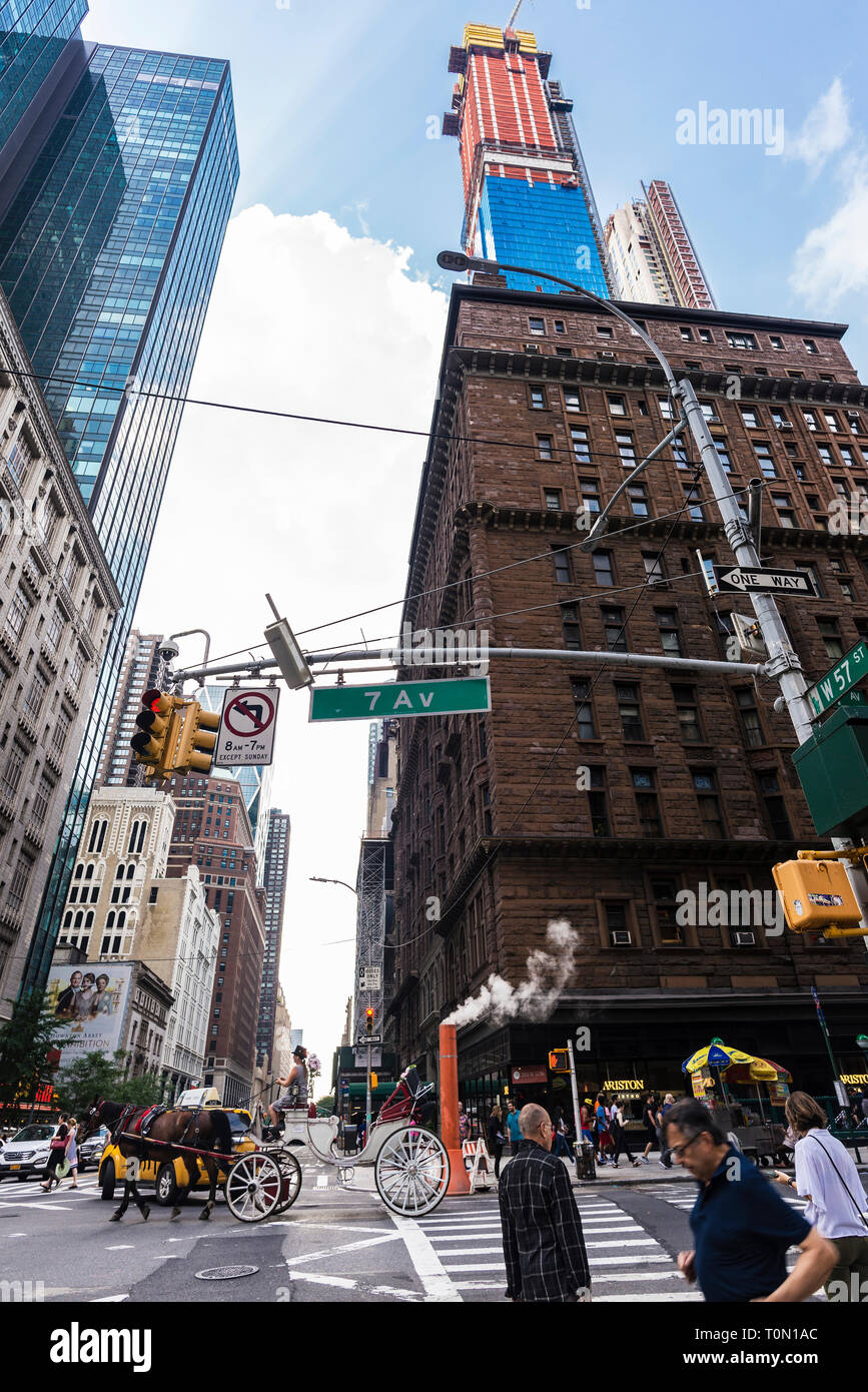 New York City, USA - July 28, 2018: Horse carriage in Seventh Avenue with people around and a smoke stack steam pipe in Manhattan, New York City, USA Stock Photo