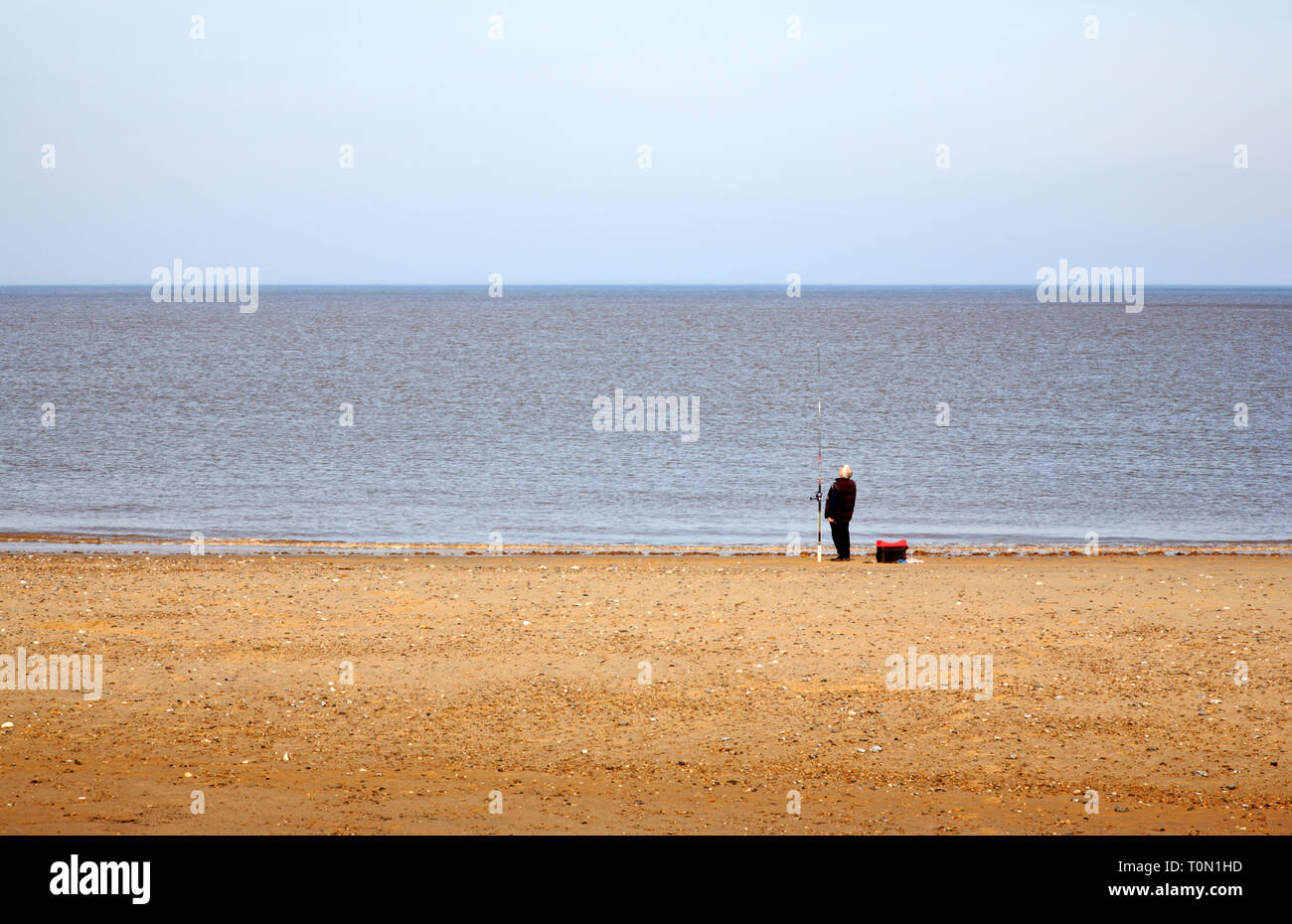 A lone sea angler on a North Norfolk beach at Bacton-on-Sea, Norfolk ...