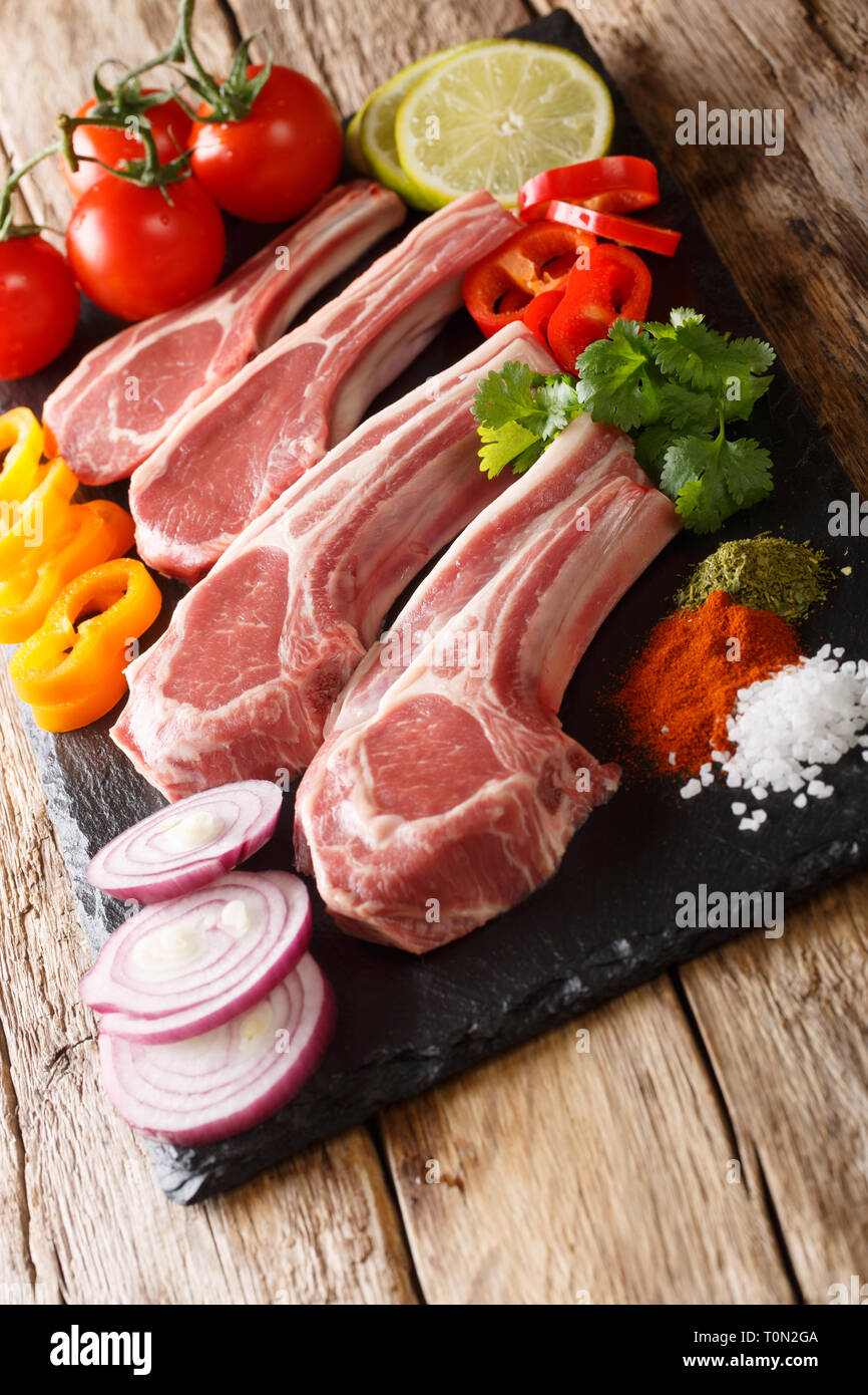 Uncooked lamb chops with fresh vegetable ingredients and spices close-up on the table. vertical Stock Photo
