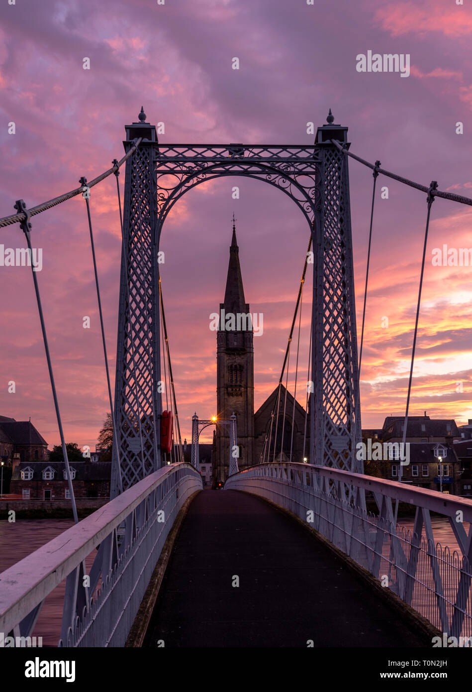 The Greig Street suspension bridge that crosses the River Ness in Inverness; framed around the Free Church of Scotland at dawn. Stock Photo
