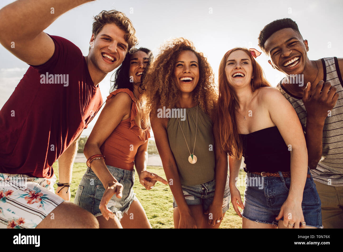Multi-ethnic group of friends together having fun. Happy young people dancing outdoors. Group of friends enjoying summer vacation. Stock Photo