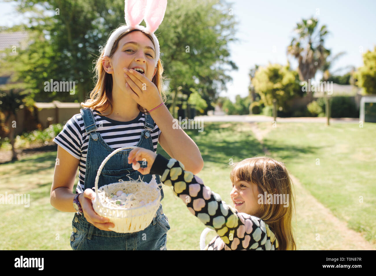 Kids eating sweets from a basket standing in a garden. Kids having fun playing in a garden on a sunny day. Stock Photo