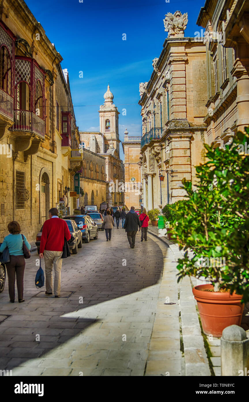 Valletta, Malta - February 18, 2013 Medieval old town typical narrow street with cars and people. Colorful red, yellow, blue green balconies and doors Stock Photo