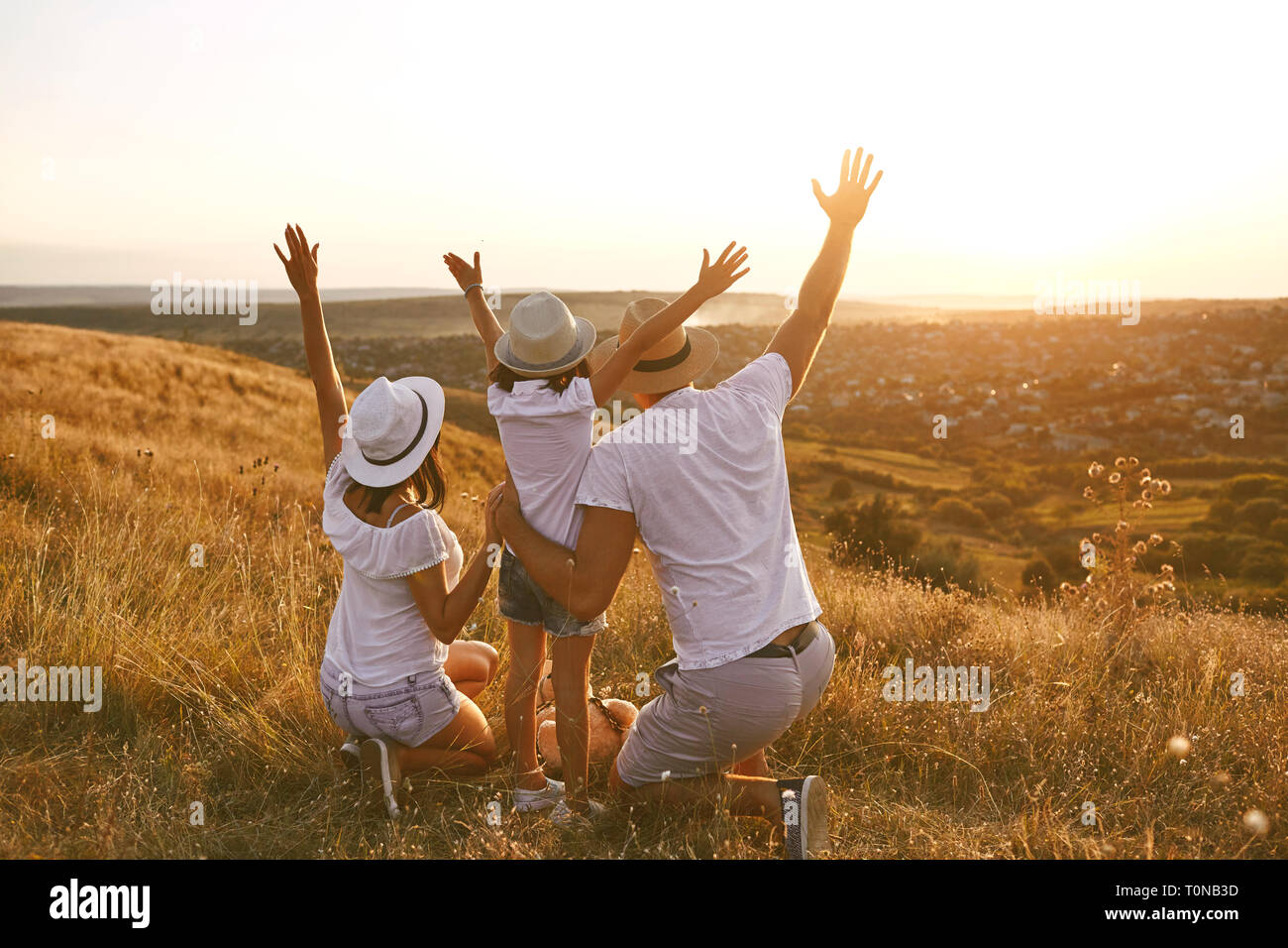 Parents with a child looking to relax at sunset on summer nature. Stock Photo