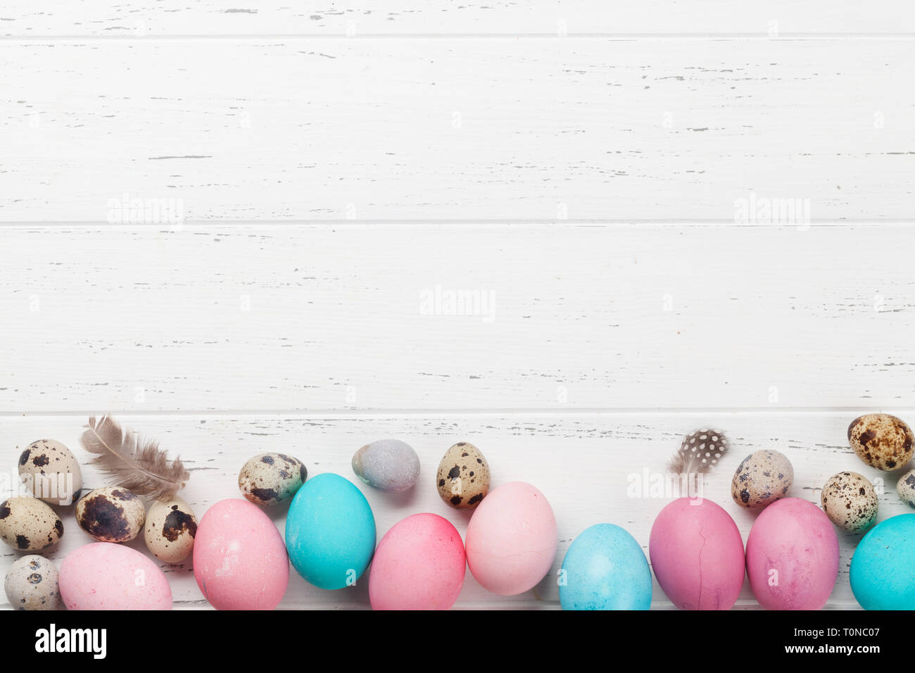 Easter greeting card with colorful eggs. Top view on wooden table with ...
