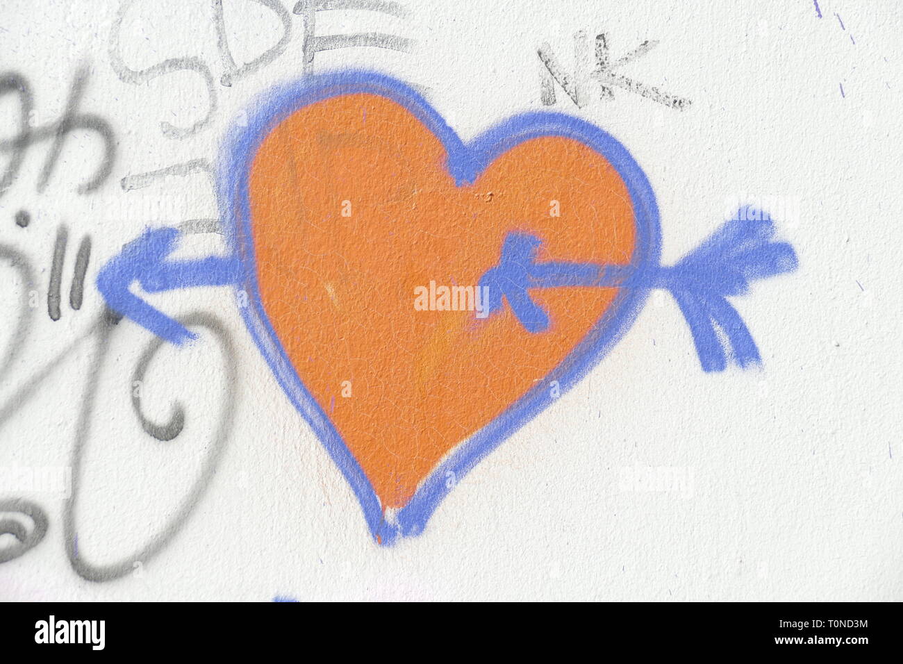 auf weisse Steinmauer gemaltes rotes Herz mit Pfeil, Symbolbild Verliebtsein Stock Photo