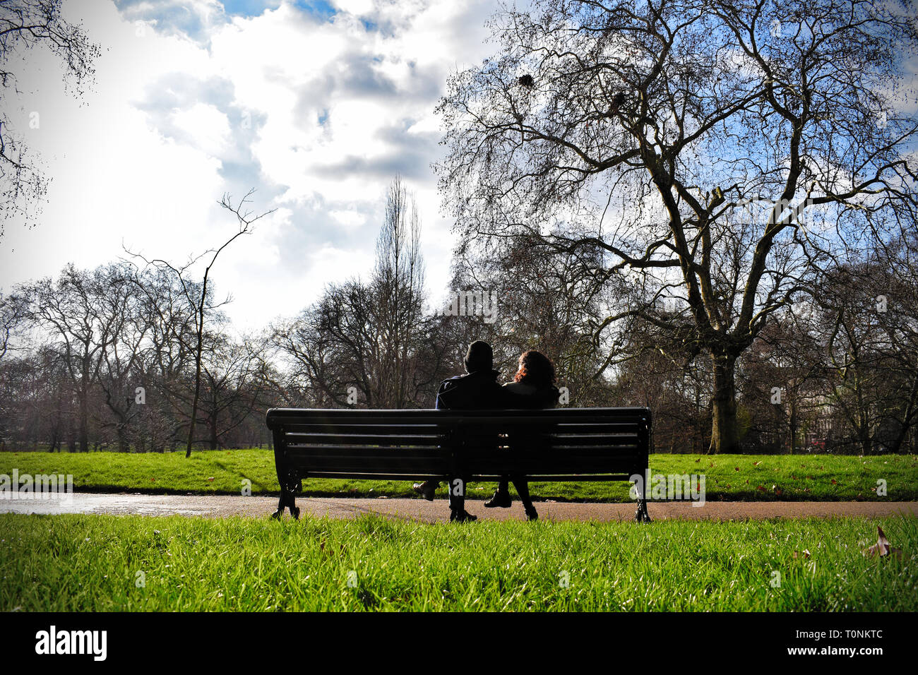 couple on a bench in a green park on a sunny day in Green park Stock Photo