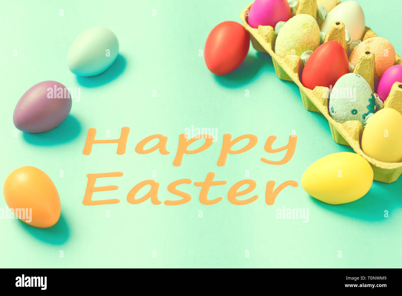 Bright Easter eggs lie in a box on a blue background Stock Photo