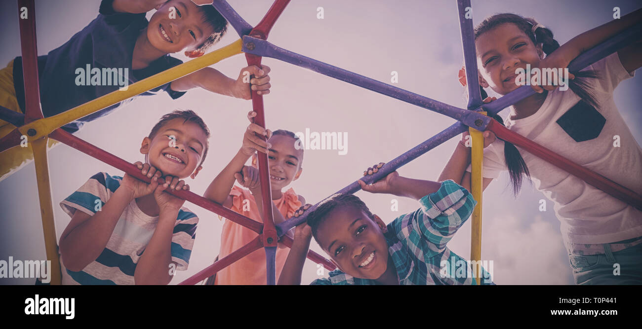 Portrait of happy schoolkids looking through dome climber Stock Photo