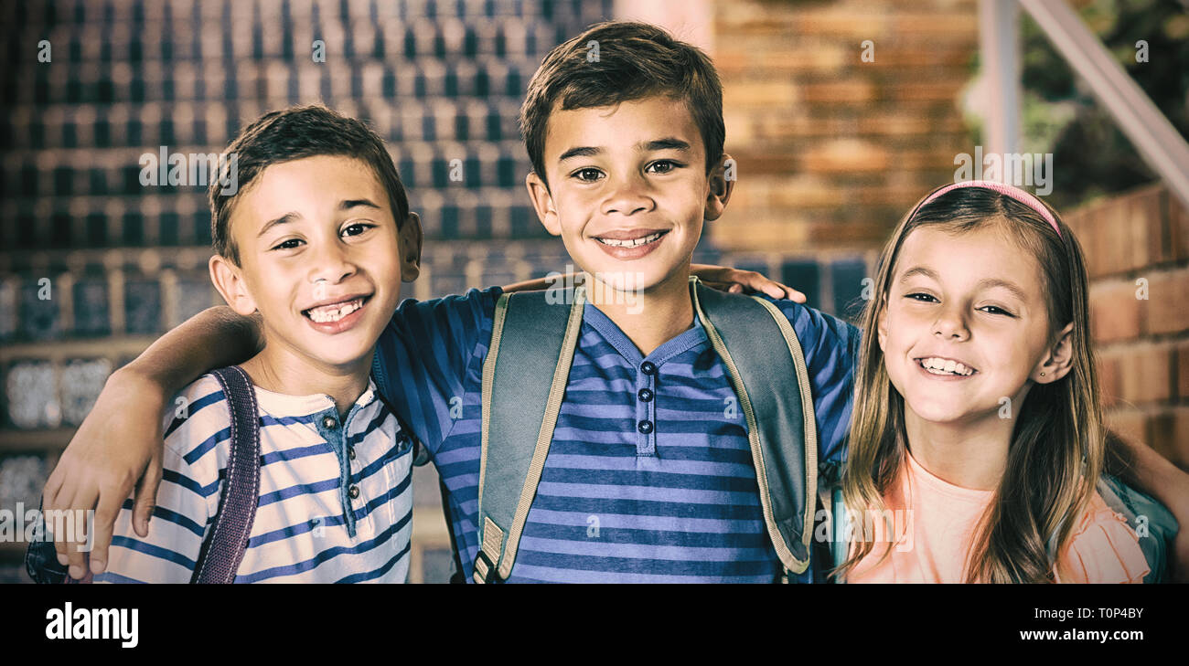 Smiling school kids standing with arm around Stock Photo