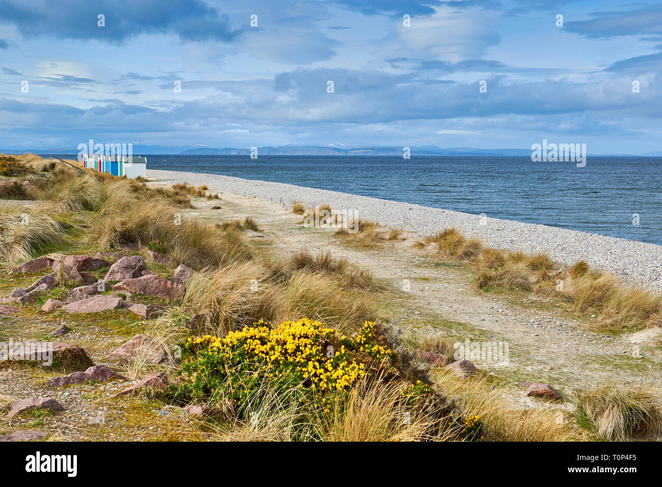 FINDHORN BEACH MORAY FIRTH SCOTLAND COLOURED CHALETS OR BEACH HUTS SNOW OVER THE HILLS AND BLACK ISLE Stock Photo