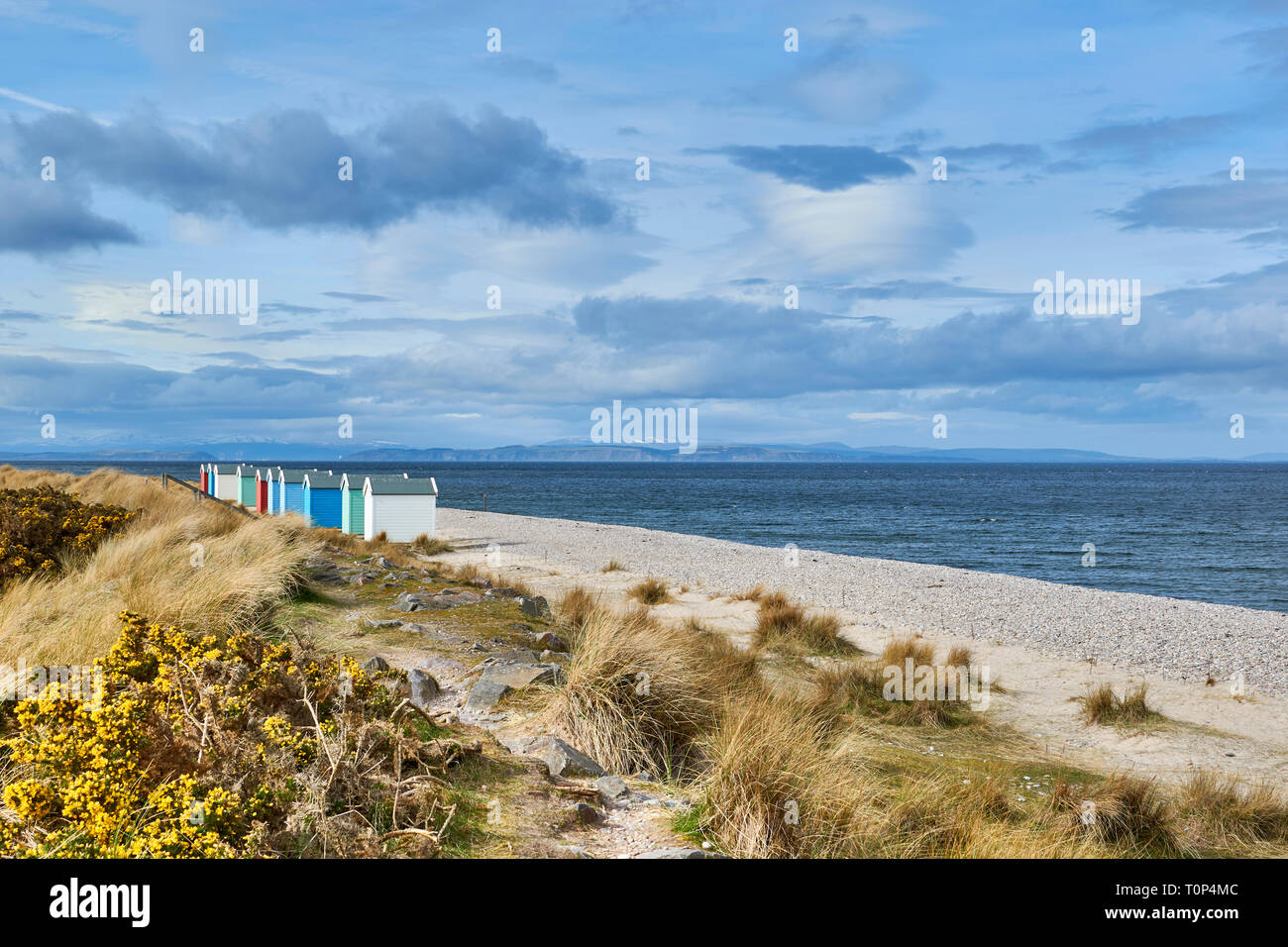 FINDHORN BEACH MORAY FIRTH SCOTLAND TEN COLOURED CHALETS OR BEACH HUTS SNOW OVER THE HILLS AND BLACK ISLE Stock Photo